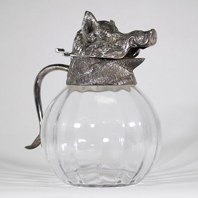 Valenti, Espagne, vers 1960 Aiguière en verre soufflé et monture en métal argenté à décor de sanglier.  Remarquable aiguière à panse godronnée en verre transparent, coiffée d’un couvercle sculptural en métal argenté figurant avec réalisme une tête de sanglier, gueule entrouverte et oreilles dressées.