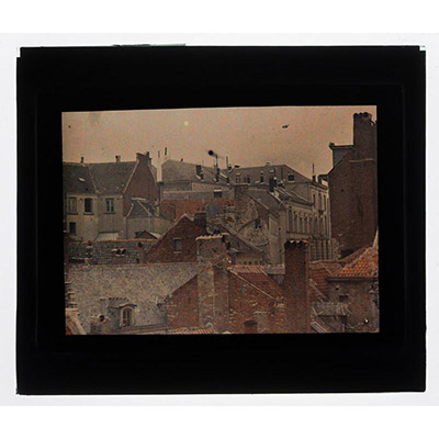 Léon Herlant (1873-1968) — 1 autochrome sur plaque Lumière, 8,5 x 10 cm.  Autochrome Vue rapprochée des Toits de Bruxelles vers 1910 — Un témoignage du Vieux Bruxelles avant la Bruxellisation  Cette vue rapprochée des toits de Bruxelles, prise vers 1910, capture la beauté intemporelle du Vieux Bruxelles, un moment de l’histoire architecturale de la ville avant sa transformation radicale par la Bru