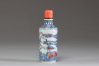 Chine - Tabatière en porcelaine blanc bleu et rouge fer à décor de dignitaires, bouchon en corail.