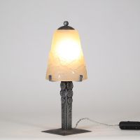 Muller Frères, Lunéville, vers 1930 Ensemble de deux lampes Art Déco en verre moulé-pressé et monture en métal ouvragé à finition nickelée mate.  Chacune des lampes repose sur une base rectangulaire en métal travaillé au repoussé, présentant une surface texturée de motifs géométriques martelés typiques de la période Art Déco. Le fût vertical, orné de pastilles et de stries régulières, soutient une