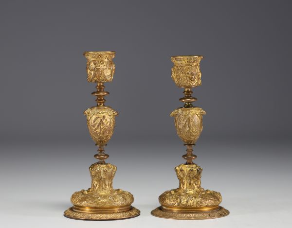 A pair of 19th century gilt bronze candlesticks, decorated with antique figures and goat heads.