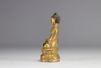Sculpture d'un bouddha assit sur un socle en bronze doré