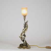 Raoul François Louche (actif au début du XXe siècle) Lampe Art Nouveau en bronze doré et patiné, verrerie signée Schneider  Rare et délicate lampe de table en bronze à patine nuancée représentant une femme nue, élancée et drapée dans un mouvement tourbillonnant, typique du style naturaliste et sensuel de l’Art Nouveau. Le personnage féminin s’élève avec grâce pour former le corps du luminaire, ses