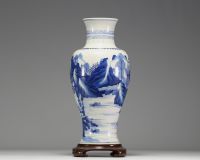 China - White and blue porcelain vase decorated with landscape and characters, wooden base, blue mark under the piece.