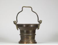 Travail brabançon, fin XVe – début XVIe siècle Seau à eau bénite en bronze avec poignée figurée  Ce rare seau à eau bénite, datable de la fin du XVe ou du début du XVIe siècle, est un bel exemple de la production de bronze liturgique dans les anciens Pays-Bas méridionaux, et plus précisément dans la région du Brabant, alors centre actif d’artisanat et de fonderie. La pièce présente une poignée mob