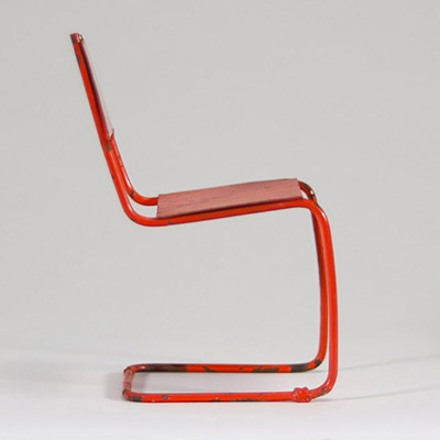 Petit jouet de style Bauhaus Chaise miniature en fer peint rouge-orangé – Vers 1930 Ce petit siège-jouet, en fer peint d’un rouge-orangé vif, évoque clairement l’univers du Bauhaus, tant par ses lignes épurées que par l’usage de matériaux industriels. L’objet n’est pas signé, mais sa forme minimaliste et fonctionnelle, ainsi que son échelle réduite, laissent penser à un jouet éducatif conçu dans l