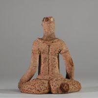 Rare statuette en terre cuite Djenné, Mali. XIème- XIVème siècle apr. J.-C. ( restauré). La figure est représentée assise, les jambes écartées et repliées symétriquement, dans une posture évoquant l’introspection ou le recueillement rituel. Le torse est orné de scarifications en damier et les seins sont traités en relief. Le visage, à la bouche proéminente, conserve des traces de pigments rouges e