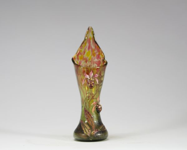 Émile Gallé – Rare vase à applications en verre émaillé, signé à la pointe « Cristallerie Gallé Nancy », première période de l’artiste Exceptionnel petit vase en verre, à décor végétal en relief appliqué et rehaussé d’émail polychrome, caractéristique des toutes premières œuvres d’Émile Gallé à Nancy. Le vase présente une forme élancée et nervurée, surmontée d’un col pointu. Décor d’orchidées styl