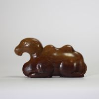 Chine, XIXe siècle. Chameau couché en jade néphrite brun, sculpté avec sobriété dans une posture stylisée, symbolisant la route de la soie et la persévérance.