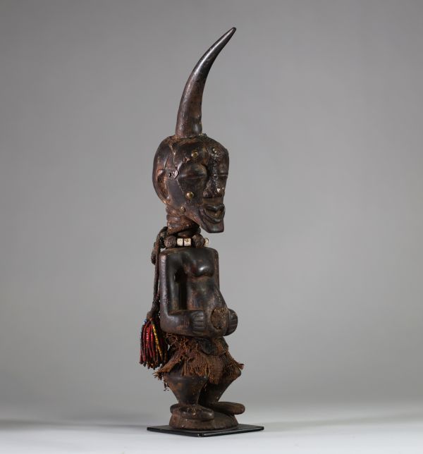 Fétiche Songye Nkisi, sous style Kalebwe, RD Congo. H : 46 cm. Figure masculine en bois, surmonté d’une corne rituelle, visage orné de clous de tapissier à fonction magique. Patine ancienne noire /brune, accessoires rituels suspendus (perles, fibres, cordelettes), cavités sous les bras. Nkisi de protection ou de justice activé par un « Nganga ». Style expressif et puissant propre aux Songye Kalebw