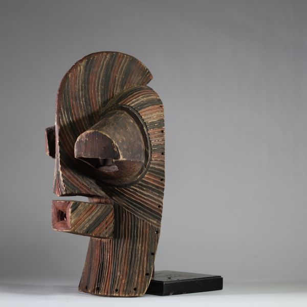 Grand masque Songye Kifwebe « Kilume ». Rd Congo. Bois. De forme allongée, une crête sagittale proéminente, une bouche saillante percée, et surtout des yeux fortement protubérants. Les stries rituelles incisées en spirale alternent des pigments bruns, noirs et ocre clair. Ce type de masque est conçu pour impressionner et symboliser les forces occultes ou sociales. La patine extérieure est mate, pr