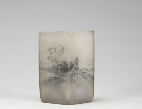 Daum Nancy, vase losangique à décor émaillé en grisaille, scène hollandaise au moulin Raffiné vase en verre opalescent de forme losangique, à décor peint en grisaille représentant une scène hollandaise avec moulin, maisons et silhouettes de voiliers. La finesse du trait et le rendu atmosphérique confèrent à cette pièce un charme poétique propre à certaines productions de la maison Daum. Signature