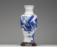 China - White and blue porcelain vase decorated with landscape and characters, wooden base, blue mark under the piece.