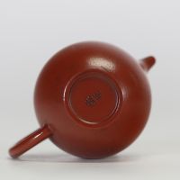 Théière globulaire en terre cuite pourpre, dite zisha, typique de la production de Yixing. Elle présente un panse arrondi, un court bec conique et une anse semi-circulaire.