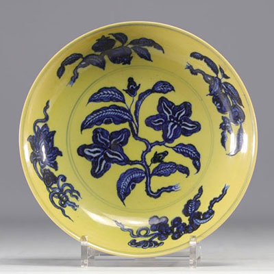 Chine - Plat en porcelaine à décor de fleurs en blanc et bleu sur fond jaune, marque en bleu.