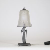 Muller Frères, Lunéville, vers 1930 Ensemble de deux lampes Art Déco en verre moulé-pressé et monture en métal ouvragé à finition nickelée mate.  Chacune des lampes repose sur une base rectangulaire en métal travaillé au repoussé, présentant une surface texturée de motifs géométriques martelés typiques de la période Art Déco. Le fût vertical, orné de pastilles et de stries régulières, soutient une