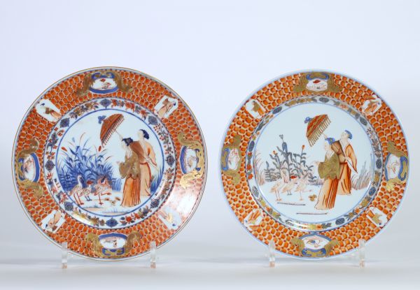 Rare paire d’assiettes en porcelaine de Chine à décor Imari de dames à l’ombrelle dans un jardin, oiseaux et insectes au revers, époque Yongzheng, XVIIIe siècle.
