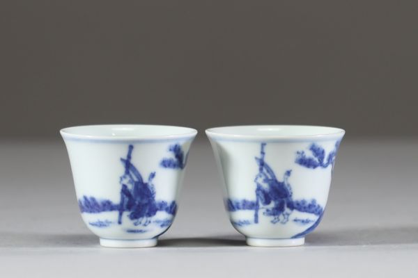Chine – Paire de petites coupes en porcelaine blanc bleu à décor de lettrés à cheval sous les pins, marque apocryphe de Kangxi  Paire de coupes évasées en porcelaine à décor en bleu sous couv