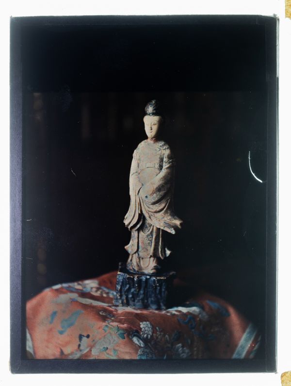 Léon Herlant (1873-1968) — 1 autochrome sur plaque Lumière, 12 x 9 cm.  Cette composition énigmatique et japonisante, captée en autochrome vers 1910, se distingue par sa radicale sobriété et son puissant effet de contraste. Sur un fond noir profond, presque pictural, n’émerge qu’un seul élément : une sculpture d’un sage japonais, à la blancheur éclatante, debout, saisie en gros plan. Son visage ca
