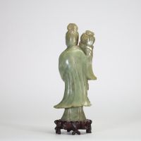 Statuette en jade céladon représentant une élégante, Chine, dynastie Qing, XIXe siècle Sculptée dans une pierre jade céladon nuancée, la figure incarne une jeune femme debout tenant un vase fleuri à l