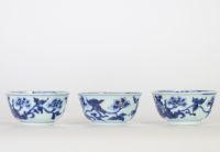 Chine, trois bols en porcelaine bleu et blanc, dynastie Qing, XVIIIe siècle, décorés de fleurs et symboles bouddhiques en léger relief au bleu sous couverte, l’intérieur orné d’une fleurette stylisée.