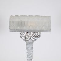France, vers 1930 Lampe de bureau Art Déco en métal martelé nickelé et verre pressé à décor floral et géométrique.  Reposant sur une base rectangulaire, cette lampe présente un fût élancé à surface martelée, d’une sobriété élégante, souligné d’une finition nickelée mate. L’ensemble est rehaussé d’un nœud ornemental de volutes forgées à la main, typique du vocabulaire décoratif de l’époque.  L’abat