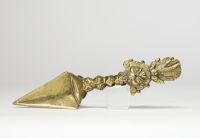 Poignard rituel bouddhique, dit phurba, en bronze doré, à triple lame triangulaire. Le manche est orné d’un nœud symbolique à facettes et se termine par une représentation expressive de Vajrakilaya. Travail tibétain, XIXe siècle.