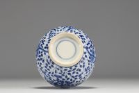 China - White-blue porcelain vase decorated with a figure holding a large covered vase, double circle mark under the piece.