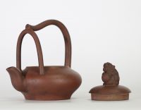 Chine, théière en grès de Yixing à anse surélevée et couvercle orné d’un lion bouddhique, XIXe siècle Théière de forme aplatie en terre cuite brune de Yixing, à anse haute ondulante et bec verseur en 