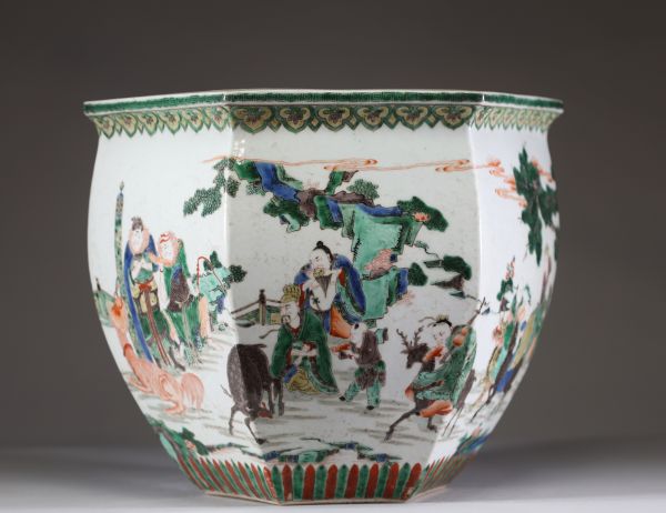 Rare et spectaculaire vase en porcelaine de forme hexagonale, décoré en émaux de la famille verte. Chaque pan du corps présente une scène animée mettant en scène des dignitaires, serviteurs et immortels dans un paysage arboré ponctué de pins, rochers et nuées stylisées. Les personnages, finement détaillés, sont représentés à cheval, à pied ou en conversation, dans un esprit narratif typique de la