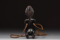 Afrique - Gabon - Amulette Lumbo en bois sculpté représentant une maternité, collier en raphia, première moitié XXème.