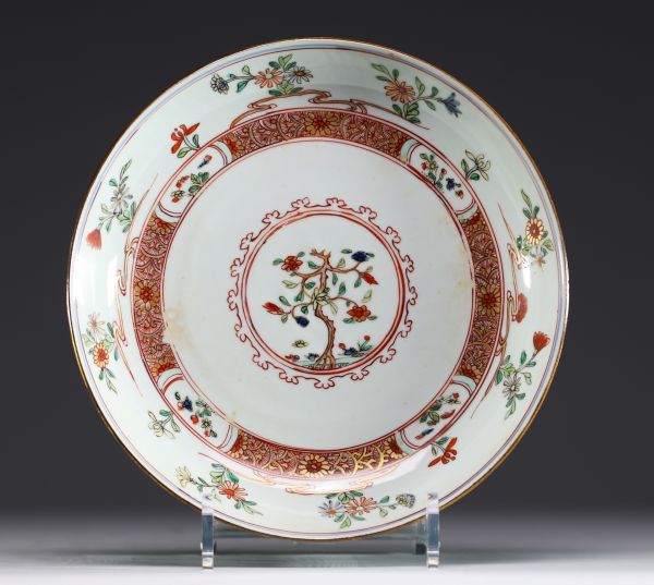 China - A polychrome porcelain plate decorated with trees and flowers, 18th century.