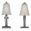 Muller Frères, Lunéville, vers 1930 Ensemble de deux lampes Art Déco en verre moulé-pressé et monture en métal ouvragé à finition nickelée mate.  Chacune des lampes repose sur une base rectangulaire en métal travaillé au repoussé, présentant une surface texturée de motifs géométriques martelés typiques de la période Art Déco. Le fût vertical, orné de pastilles et de stries régulières, soutient une