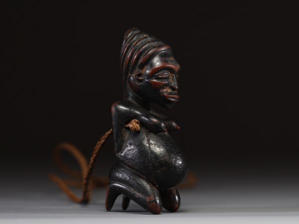 Afrique - Gabon - Amulette Lumbo en bois sculpté représentant une maternité, collier en raphia, première moitié XXème.