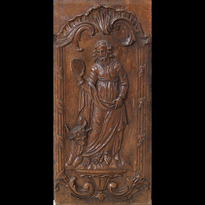 Panneau en chêne finement sculpté en haut relief, figurant saint Luc. L’évangéliste est représenté debout, en tunique et manteau, tenant dans sa main droite un objet circulaire. L’ensemble est encadré d’un riche décor rocaille à enroulements feuillagés et coquille.Travail régional, probablement d’Europe du Sud ou de l’Est, d’époque XVIIIe siècle.