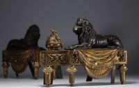 Paire de chenets en bronze patiné et doré représentant des lions couchés devant une flamme, XIXème.