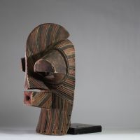 Grand masque Songye Kifwebe « Kilume ». Rd Congo. Bois. De forme allongée, une crête sagittale proéminente, une bouche saillante percée, et surtout des yeux fortement protubérants. Les stries rituelles incisées en spirale alternent des pigments bruns, noirs et ocre clair. Ce type de masque est conçu pour impressionner et symboliser les forces occultes ou sociales. La patine extérieure est mate, pr