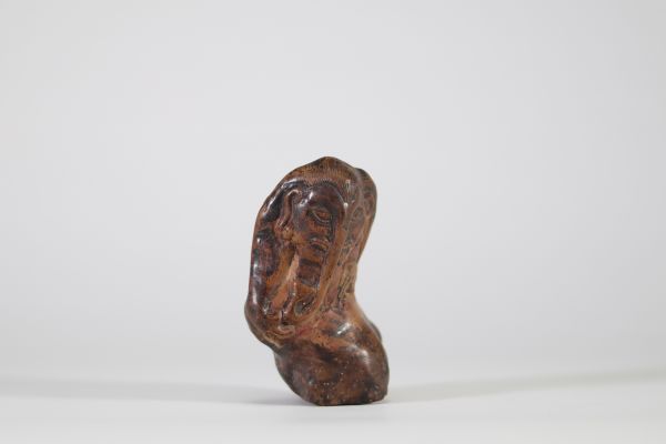 Fragment sculpté en pierre représentant une figure anthropomorphe à trompe, probablement Ganesh. Inde ou Himalaya, XIXe siècle. La composition s’intègre harmonieusement aux irrégularités naturelles du galet, caractéristique d’un travail rituel populaire, probablement issu d’un contexte religieux localisé dans le nord de l’Inde ou les régions himalayennes. L’objet pourrait avoir servi de talisman p