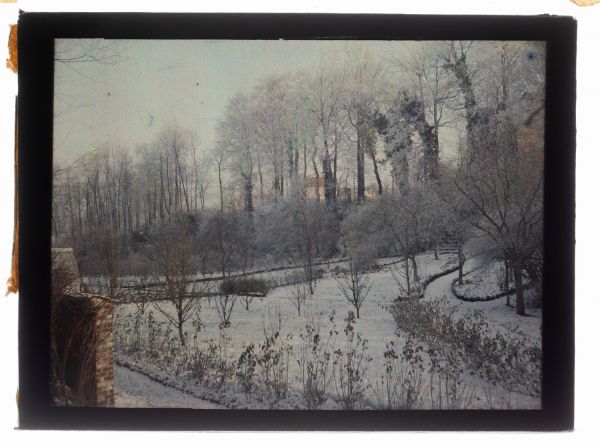 Léon Herlant (1873-1968) — autochrome sur plaque Lumière», 12 x 9 cm.  Paysage de Watermael-Boitsfort sous la neige, Sous la lumière douce et dorée d’un matin d’hiver, ce paysage enneigé déploie une atmosphère magique et silencieuse, empreinte de mystère. La scène évoque irrésistiblement l’univers de Pieter Bruegel l’Ancien, par son traitement poétique de la nature figée et son rendu sensible des