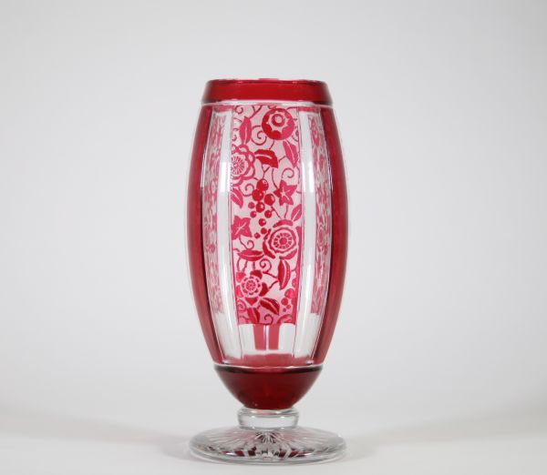 Vase Art Déco en cristal doublé rouge à décor géométrique et floral, attribué à Baccarat Vase de forme balustre en cristal doublé rouge rubis, à décor géométrique structuré par des pans coupés verticaux alternant motifs lisses et réserves gravées à l’acide d’un décor floral stylisé. Le corps repose sur un piédouche circulaire taillé en étoile.
