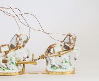 Centre de table à décor de carrosse tiré par quatre chevaux, en bronze ciselé et doré, la scène animée de figures en porcelaine polychrome, représentant deux jeunes enfants dans une calèche ornée de volutes feuillagées et de guirlandes fleuries. Les chevaux sont en porcelaine, fixés sur des bases en porcelaine émaillée à décor fleuri. Travail de style rococo, probablement allemand ou viennois, ver