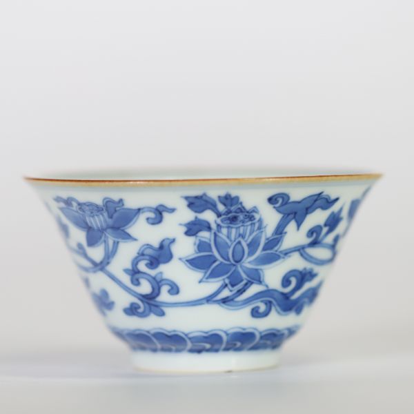 Chine, bol en porcelaine blanc-bleu à décor de fleurs de lotus épanouies et en bouton surmontant une frise de vagues, l'intérieur orné d'une fleur stylisée et la base portant une marque apocryphe à si