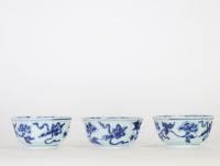 Chine, trois bols en porcelaine bleu et blanc, dynastie Qing, XVIIIe siècle, décorés de fleurs et symboles bouddhiques en léger relief au bleu sous couverte, l’intérieur orné d’une fleurette stylisée.