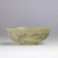 Bol en jade céladon finement gravé d’un paysage montagneux et d’un poème calligraphié, marqué Qianlong  Bol circulaire en jade de teinte céladon très pâle, finement incisé d’un décor continu représent