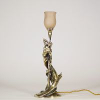 Raoul François Louche (actif au début du XXe siècle) Lampe Art Nouveau en bronze doré et patiné, verrerie signée Schneider  Rare et délicate lampe de table en bronze à patine nuancée représentant une femme nue, élancée et drapée dans un mouvement tourbillonnant, typique du style naturaliste et sensuel de l’Art Nouveau. Le personnage féminin s’élève avec grâce pour former le corps du luminaire, ses