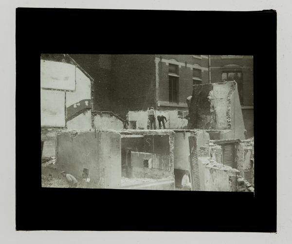 Léon Herlant (1873-1968) — 2 photos positives sur plaques de verre, 8,5 x 10 cm.  Cet ensemble de deux plaques photo positives noir et blanc capture la scène d’un chantier urbain à Bruxelles au 19e siècle, probablement dans la rue du Marais, une rue emblématique de la ville. La scène prend place dans un quartier où l’architecture néo-classique bruxelloise est omniprésente. Les bâtiments à l’esthét