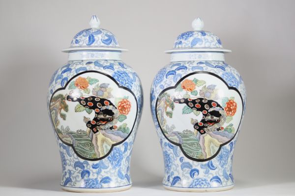 Asie, XXᵉ siècle – Paire de potiches couvertes en porcelaine à décor de lions en cartouches sur fond floral bleu et blanc
