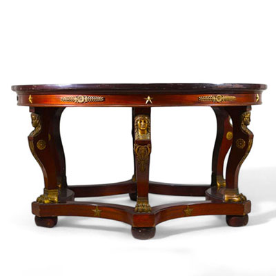Rare table guéridon d'époque Empire à six pieds en volute surmontés de têtes de cariatides et se terminant par des pates de fauves en bronze doré.
