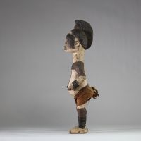 Statue Igbo « Alusi ». Nigéria. Bois, textile. Représentation masculine de type Alusi, divinité secondaire ou esprit tutélaire propre au peuple Igbo (sud-est du Nigeria), vénérée dans des sanctuaires collectifs ou familiaux. Grande crête sagittale sculptée d’une coiffe en éventail semi circulaire, ornée de motifs en spirales. Front bombé, yeux globuleux en amande, sans pupille, sourcils et joues m