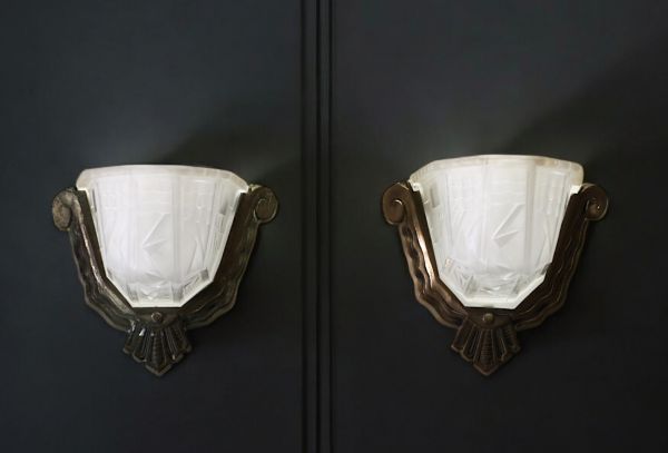 A pair of Art Deco sconces in pressed moulded glass with geometric motifs and silvered bronze mountings, circa 1930.